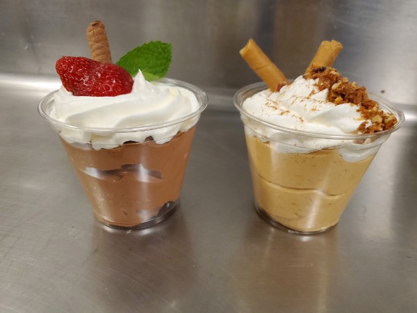Two dessert cups side by side — chocolate topped with a strawberry, peanut butter dusted with toffee crumble.